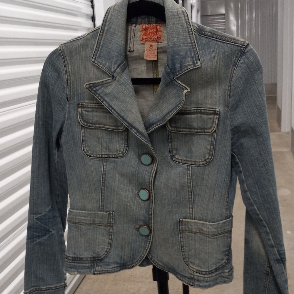 Fitted denim jacket with turquoise colored buttons.